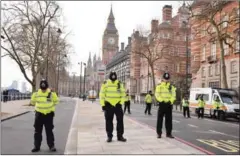  ?? JUSTIN TALLIS/AFP ?? British police officers bow their heads as they stand directly outside New Scotland Yard in central London yesterday during a minute of silence to commemorat­e the victims of the attack.