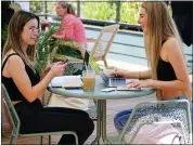  ??  ?? Emma Green, left, and Ava Hallin sip coffee drinks and use their laptops on the rooftop seating area Wednesday at Stoble Coffee and Workplace in Chico.