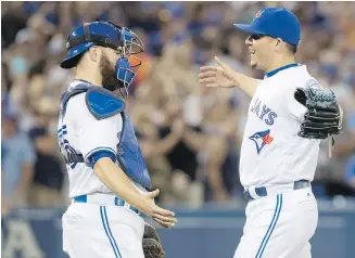  ??  ?? Blue Jays catcher Russell Martin and closer Roberto Osuna celebrate after beating the Rays in Toronto on Monday.