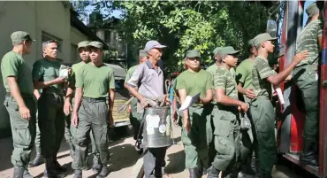  ??  ?? A Sri Lankan municipal worker, middle, along with soldiers leave for dengue fever eradicatio­n work in Colombo.