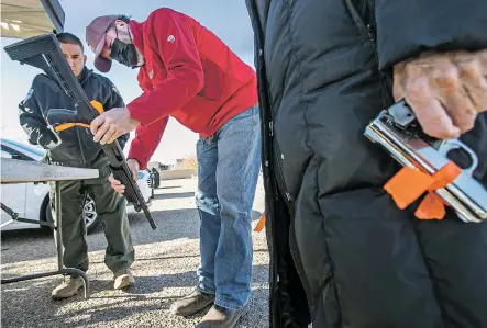  ?? JIM WEBER/NEW MEXICAN FILE PHOTO ?? Officer Gerald Lovato, left, and volunteer Garrett VeneKlasen try to spot the serial number on a shotgun in 2021 during a gun buyback event organized by the Santa Fe Police Department in conjunctio­n with New Mexicans to Prevent Gun Violence.