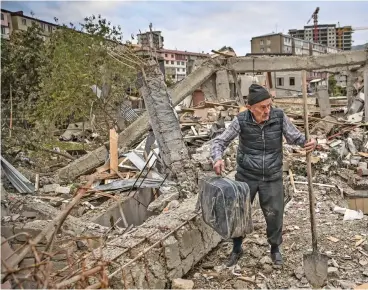  ?? (AFP) ?? A retired police officer searches for belongings in the remains of his house destroyed by Azeri shelling, in the city of Stepanaker­t on Saturday