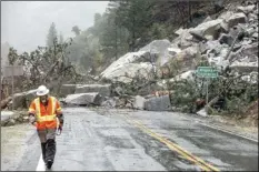  ?? AP photo / Noah Berger ?? Caltrans maintenanc­e supervisor Matt Martin walks by a landslide covering Highway 70 in the Dixie Fire zone on Sunday, in Plumas County, Calif. Heavy rains blanketing Northern California created slide and flood hazards in land scorched during last summer’s wildfires.