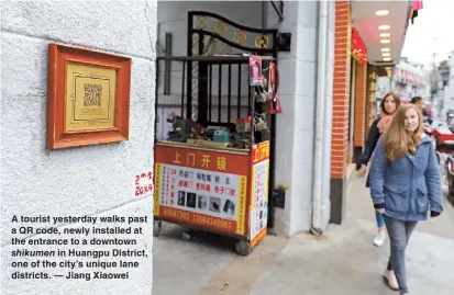  ??  ?? A tourist yesterday walks past a QR code, newly installed at the entrance to a downtown shikumen in Huangpu District, one of the city’s unique lane districts. — Jiang Xiaowei