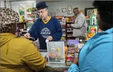  ?? Stephanie Strasburg/Post-Gazette ?? Tim Doman, left, hands “food bucks” back to customers as Carl Lewis, back, owner of Carl’s Cafe, answers a phone call about food stamp benefits Wednesday in Rankin.