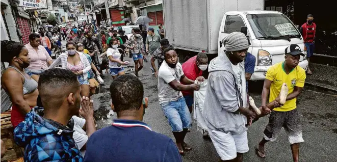  ?? Ricardo Moraes - 15.mai.20/Reuters ?? Moradores carregam corpos de pessoas baleadas durante operação policial no Complexo do Alemão, no Rio, que terminou com 12 mortos