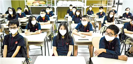  ?? — AFP photo ?? Students wearing face masks sit inside a classroom at the Marie Curie school in Hanoi.