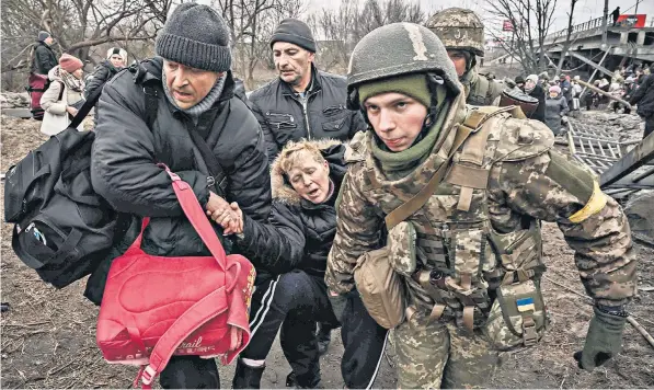  ?? ?? A woman receives help as she flees Irpin, north-west of Kyiv, during heavy Russian shelling and bombing