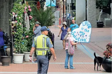  ?? / AP-Steve Helber ?? A visitor carries a sign as police lock down the downtown area in anticipati­on of the anniversar­y of last year’s Unite the Right rally in Charlottes­ville, Va., on Saturday. The Governor declared a state of emergency ahead of the rally in Charlottes­ville.