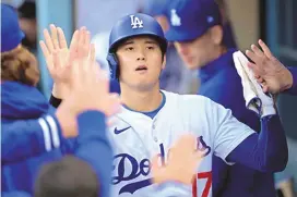  ?? JAYNE KAMIN-ONCEA/ASSOCIATED PRESS ?? Los Angeles Dodgers designated hitter Shohei Ohtani is greeted in the dugout after scoring against the St. Louis Cardinals during the sixth inning of Sunday’s game in Los Angeles. Ohtani went 1-for-4 with a double.