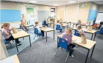  ?? OLI SCARFF AFP VIA GETTY IMAGES ?? Children eat their lunches at their desks in England on Thursday. On Wednesday, Sick Kids hospital recommende­d schools in Ontario be reopened for the well-being of the children.