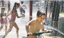  ?? ALLEN MCINNIS ?? Nathaniel Verzamanis is delighted as he rides his bike through the splash pad installati­ons at Parc de Lestre on Wednesday.