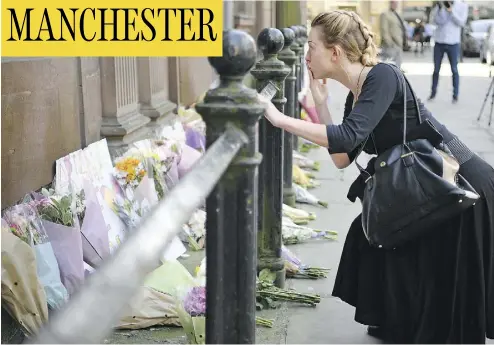  ?? JEFF J MITCHELL / GETTY IMAGES ?? A woman reflects by the flowers left in Manchester’s St. Ann Square on Tuesday, a day after a suicide bombing at a pop concert that killed 22 people in the worst terror incident on British soil since the London bombings of 2005.