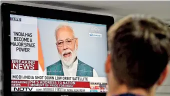  ??  ?? A man watches Prime Minister Modi's address during which he announed that an anti-satellite missile test had put the country in the space “super league”. AFP