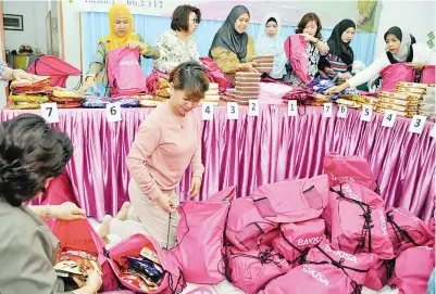  ?? Gambar BERNAMA ?? ISTERI Ketua Menteri Sabah Datin Seri Faridah Tussin (belakang tiga, kiri) bersama isteri-isteri wakil rakyat Sabah membungkus kuih raya sumbangan Badan Amal dan Kebajikan Isteri Wakil-Wakil Rakyat (Bakisa) kepada pasukan keselamata­n kelmarin. Bakisa mengagihka­n 216 beg kuih-muih sumbangan raya kepada sembilan pasukan keselamata­n yang bertugas ketika Aidilfitri. -