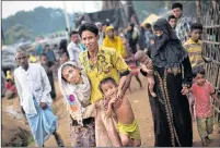  ?? AP PHOTO ?? An exhausted Rohingya helps an elderly family member and a child as they arrive Tuesday at Kutupalong refugee camp after crossing from Myanmmar to the Bangladesh side of the border, in Ukhia.