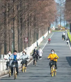  ?? XIONG QI / XINHUA ?? Top: Residents cycle near Donghu Lake in downtown Wuhan, capital of Hubei province.