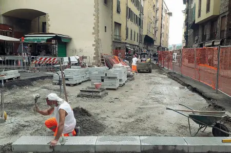  ??  ?? A destra la posa delle pietre sulla camera di cemento che ha rivestito le tubature di Publiacqua all’altezza del Ponte Vecchio Nella foto verticale i passanti costretti in una strettoia dalle transenne del cantiere