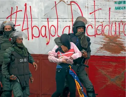  ??  ?? Riot police detain a demonstrat­or during a rally against Venezuelan President Nicolas Maduro’s government in Caracas yesterday. The graffiti behind them reads ‘‘Down with the dictatorsh­ip’’.