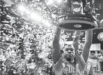  ?? Jamie Squire / Getty Images ?? Guard DeJon Jarreau hoiststhe NCAA Tournament Midwest Regional championsh­ip trophy after the Cougars beat the Oregon State Beavers to advance to the Final Four in March.