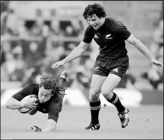  ??  ?? Leading by example... Tana Umaga, the All Black captain, dives over the line to score New Zealand’s first try during their 23-19 victory at Twickenham yesterday. His team-mate, Doug Howlett enjoys the moment