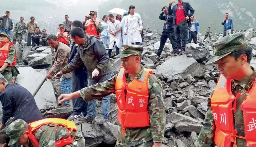  ?? — AFP ?? Emergency personnel and local people work at the site of a landslide in Xinmo village in southweste­rn China’s Sichuan Province, on Saturday.