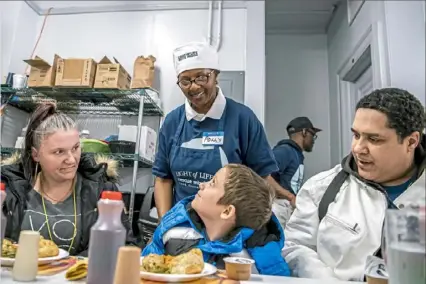  ?? Pittsburgh Post-Gazette ?? Volunteer Polly Stewart of Highland Park joins Krystal, Dylan, 7, and AJ Jones of Perry North in a prayer before a Thanksgivi­ng meal Thursday at the Light of Life Rescue Mission on the North Side.