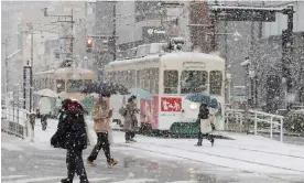  ?? Photograph: JIJI Press/AFP/Getty Images ?? People cross the street in Toyama, Japan, as parts of the country endure a severe cold snap.