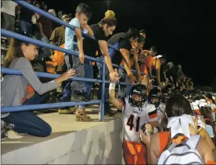  ?? Arcenio J. Trujillo ?? Acknowledg­ing their fans after each game is a staple in the Taos Tigers’ playbook. Here, Brian Moraga makes his way down the hero’s gauntlet as the visiting crowd and the Tiger cheer team clamor to offer their congratula­tions after the Tigers defeated the Santa Fe High School Demons Sept. 14.