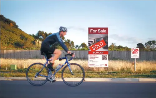  ?? JASON REED / REUTERS ?? A cyclist passes by a plot of land where a home costing more than A$1 million ($768,900) was to be built, in the new Sydney suburb of Greenhills Beach, on May 13, 2014.