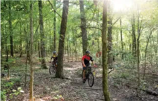  ?? Staff photo by Kelsi Brinkmeyer ?? ■ Krista Anderson and T.J. Coltharp bike along the Bringle Lake Park biking trail. The trail is roughly 7.5 miles long and is funded and maintained by the public.