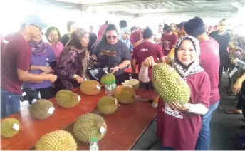  ??  ?? Rosey holds a big-sized durian at one of the booths.