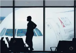  ?? CHARLIE RIEDEL/AP ?? A man in a face mask to help prevent the spread of COVID-19 waits for a Delta Air Lines flight in February at Hartsfield-Jackson Internatio­nal Airport in Atlanta .