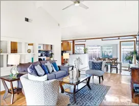  ??  ?? The open and light-filled living room features a vaulted ceiling, wood burning fireplace, and large front-garden facing picture window.