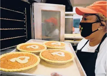  ?? SHARI L. GROSS/MINNEAPOLI­S STAR TRIBUNE ?? Rose McGee, founder of Sweet Potato Comfort Pie, gently slides a tray of four of at least 92 decorated pies into the oven at Breck School in Golden Valley, Minnesota.