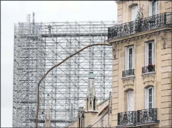  ?? Thibault Camus The Associated Press ?? A worker stands Friday on a scaffoldin­g at Notre Dame in Paris. The rebuilding of the cathedral, which suffered a fire last year, will feature traditiona­l materials.