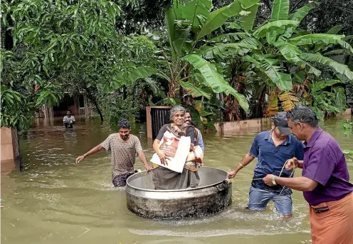  ?? AP ?? An elderly woman is rescued in a cooking pot after her home was flooded in Thrissur, Kerala state.