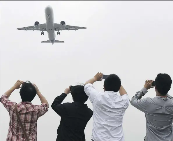  ??  ?? Spectators take photos as the Comac C919 passes overhead on its maiden flight at Shanghai’s Pudong airport on May 5. Comac, China’s state-owned
