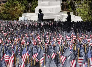  ?? ELISE AMENDOLA / AP ?? People in Boston view flags placed there for Memorial Day. The solemn display of thousands of U.S. flags — a flag garden — first appeared on Boston Common a decade ago to honor fallen service members.