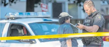  ?? RICK MADONIK/TORONTO STAR ?? A police officer takes notes outside a parking lot near the site of a shooting in a Scarboroug­h playground on Thursday.