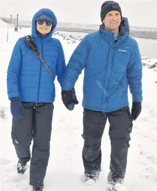  ?? DAVE STEWART • THE GUARDIAN ?? Sandra Doherty and Paul Coles are bundled up against the wind and sleet as they enjoy a brisk walk on the boardwalk in Charlottet­own's Victoria Park on Tuesday afternoon.