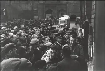  ??  ?? Below: Waiting relatives listen to an official read a list of names after an accident at the Creswell Colliery, 1950, which claimed the lives of 80 miners Bottom right: One of Denis’s earliest photograph­s, showing his mother Laura ironing at home in Mansfield