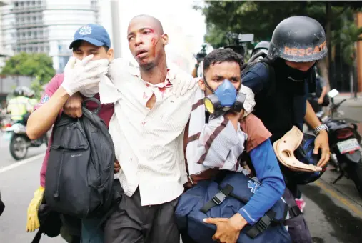  ??  ?? Paramedics assist a man injured during clashes with security forces during protests in Caracas, Venezuela. (AP)