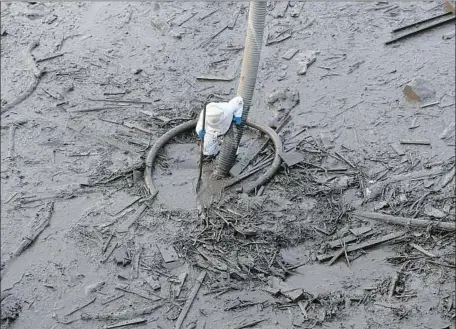  ?? Photograph­s by Michael Owen Baker For The Times ?? A WORKER HELPS remove mud from U.S. 101 on Sunday. “Highway 101 will reopen,” a Caltrans spokesman said. “I just can’t say when.”