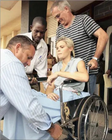  ?? Picture: REUTERS ?? WHEELED TO FREEDOM: Assistant producer Kathryne Fuller is assisted by Brad Nathanson (left) a private SA investigat­or, and her father Steward Fuller (right) as she leaves court after pleading guilty to a charge of using cocaine in the Ugandan capital...