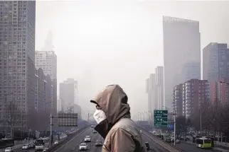  ?? QILAI SHEN/BLOOMBERG ?? A person walks on a footbridge with buildings shrouded in haze in the background in Beijing in 2017.