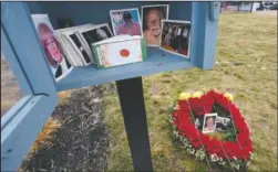  ?? (AP/Elise Amendola) ?? Photos of loved ones are seen on a floral arrangemen­t and wooden box Monday in Lynnfield, Mass. When artist Kristina Libby started the Floral Heart Project to give the survivors of covid-19 victims places to mourn, she was thinking of people who lost their loved ones and who were unable to see them in their last moments nor have funeral services.