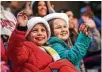  ??  ?? Abigail Smith, 10, left, and her cousin Emily Clay, 7, wave to Santa Claus.