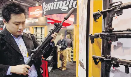  ?? AP ?? Kevin Kao examines a military-grade Remington adaptive combat rifle at the 35th annual Shot Show in Las Vegas. Remington Outdoor Company filed for bankruptcy protection, after years of falling sales and lawsuits tied to the Sandy Hook Elementary School...