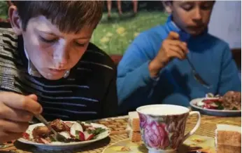  ?? MSTYSLAV CHERNOV PHOTOS/THE ASSOCIATED PRESS ?? Viktoria Vetrova’s sons Bogdan, left, and Kolya, eat at home in Zalishany, Ukraine. Eight-year-old Bogdan suffers from an enlarged thyroid and Vetrov suspects it’s caused by contaminat­ed food.